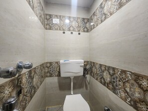 Et badeværelse med toilet, håndvask og bruseområde.