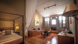 A bedroom with a four-poster bed, a sofa, a chair, and a desk with a lamp. - Argus Residence (George Town)