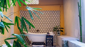 A bathroom with a bathtub, a potted plant, and a checkered floor. - Argus Residence (George Town)