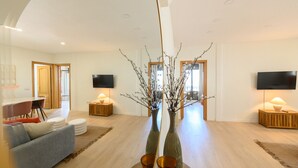 A modern living room with a sofa, a coffee table, and two side tables with lamps. There are two flat-screen TVs mounted on the walls. - Two bedroom flat-Terrace and balcony in Madrid (Madrid)