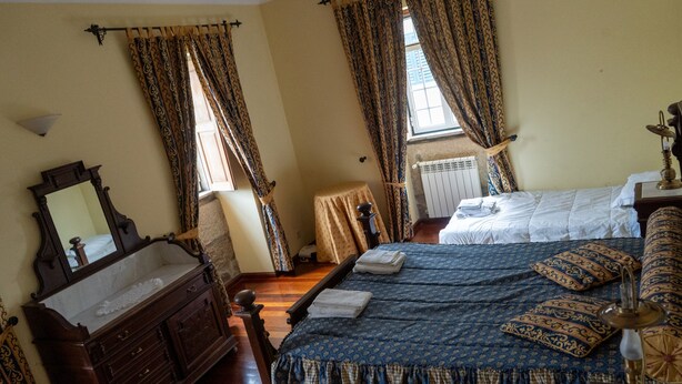 A traditional bedroom with a wooden bed, a nightstand, a dresser, and a large mirror. - Four Seasons Private Pool Huge Palace (Celorico da Beira)