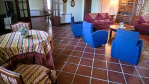 A spacious living room with a tiled floor, a patterned table, and blue armchairs. - Four Seasons Private Pool Huge Palace (Celorico da Beira)