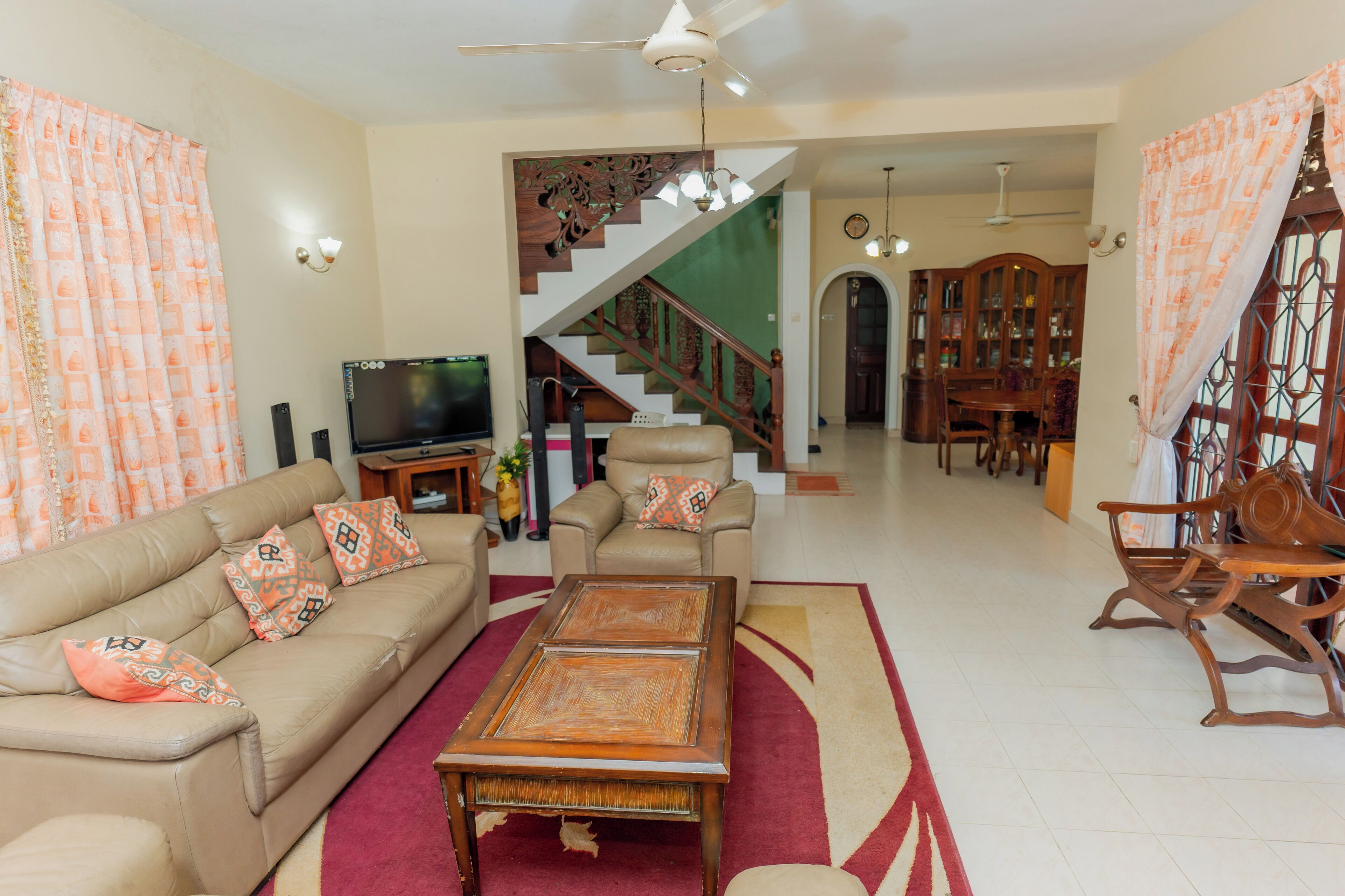 A living room with a sofa, coffee table, TV, and a staircase leading to another room.