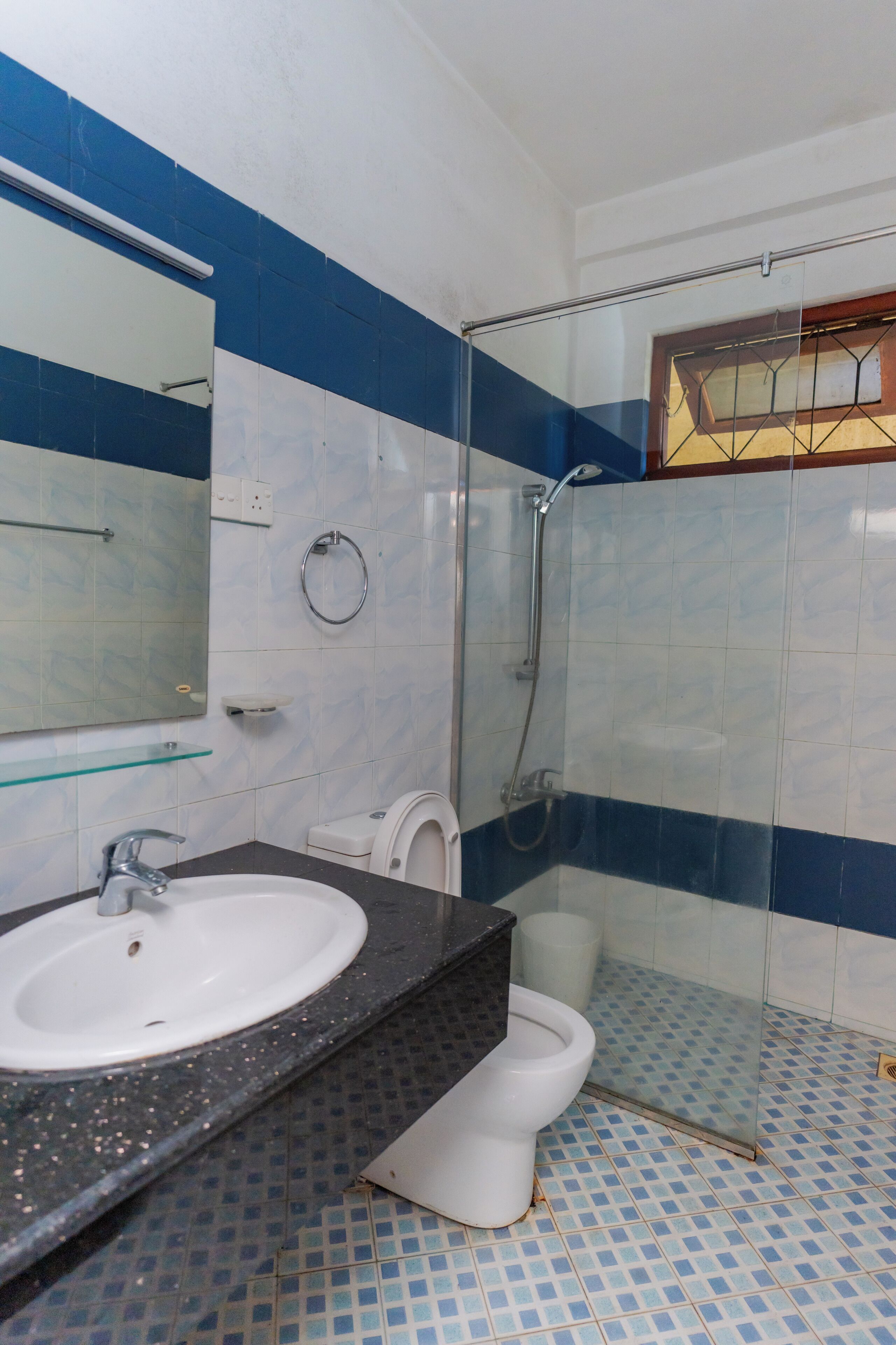 Et badeværelse med et hvidt håndvask, toilet, glas brusekabine og et spejl.