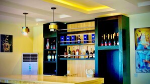 A bar area with a wooden counter, shelves with bottles, and a ceiling with recessed lighting. - Slavan Suites & Apartments (Owerri)