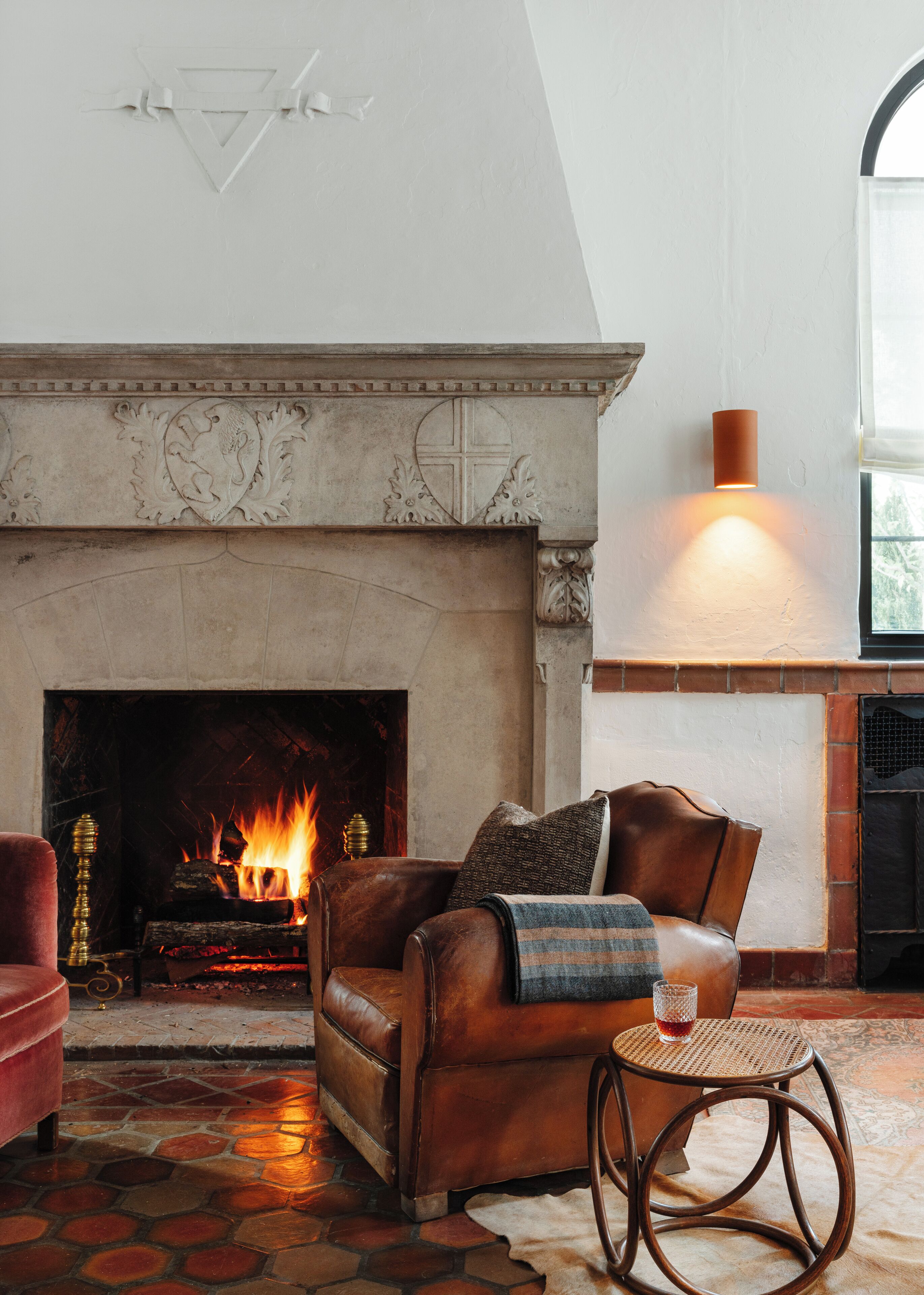 A cozy living room with a fireplace, leather sofa, and a round wooden table.