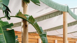 A bed with striped bedding, a wooden headboard, and a canopy with green tassels. - The Landing Social House (Chattanooga)