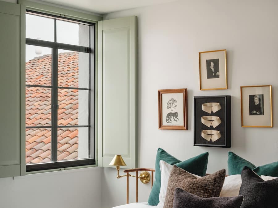 Een slaapkamer met een bed, kussens, een raam en wanddecoratie.