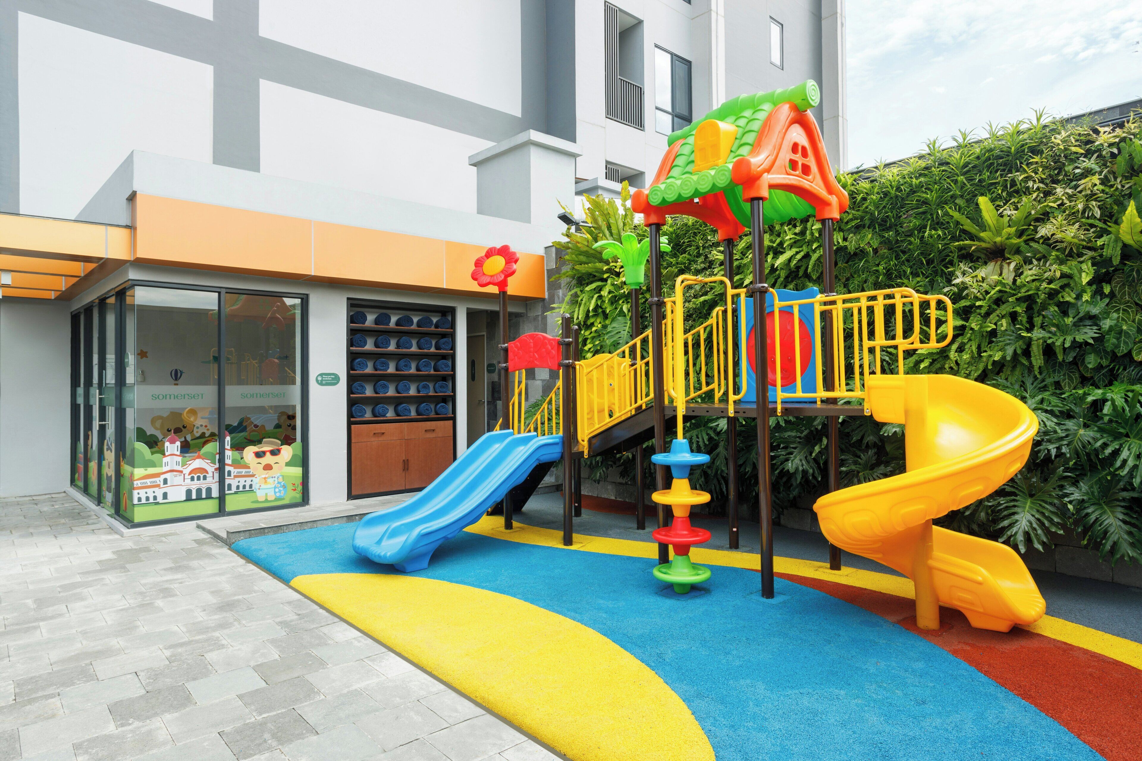 Zona de juegos infantiles con tobogán, estructura para escalar y suelo de colores.