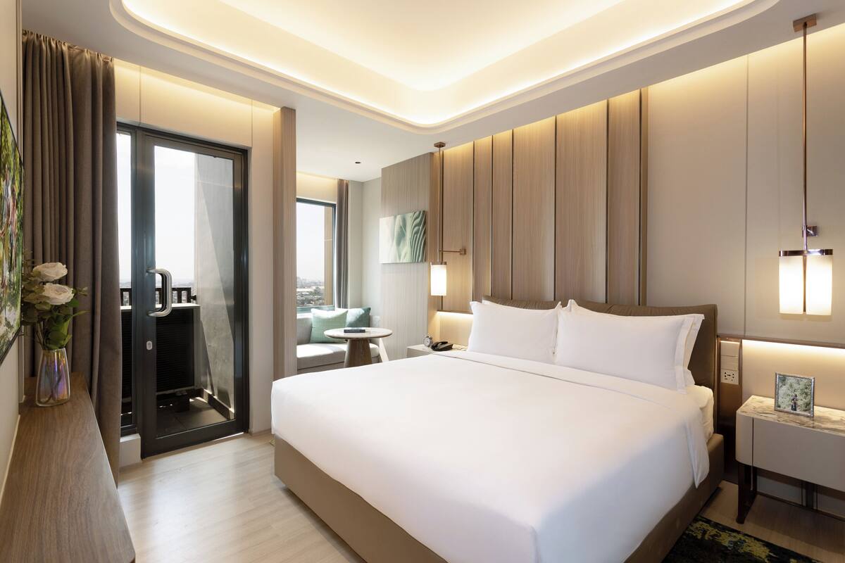 Une chambre d’hôtel moderne avec un grand lit, des tables de chevet, un bureau et une vue sur la ville.