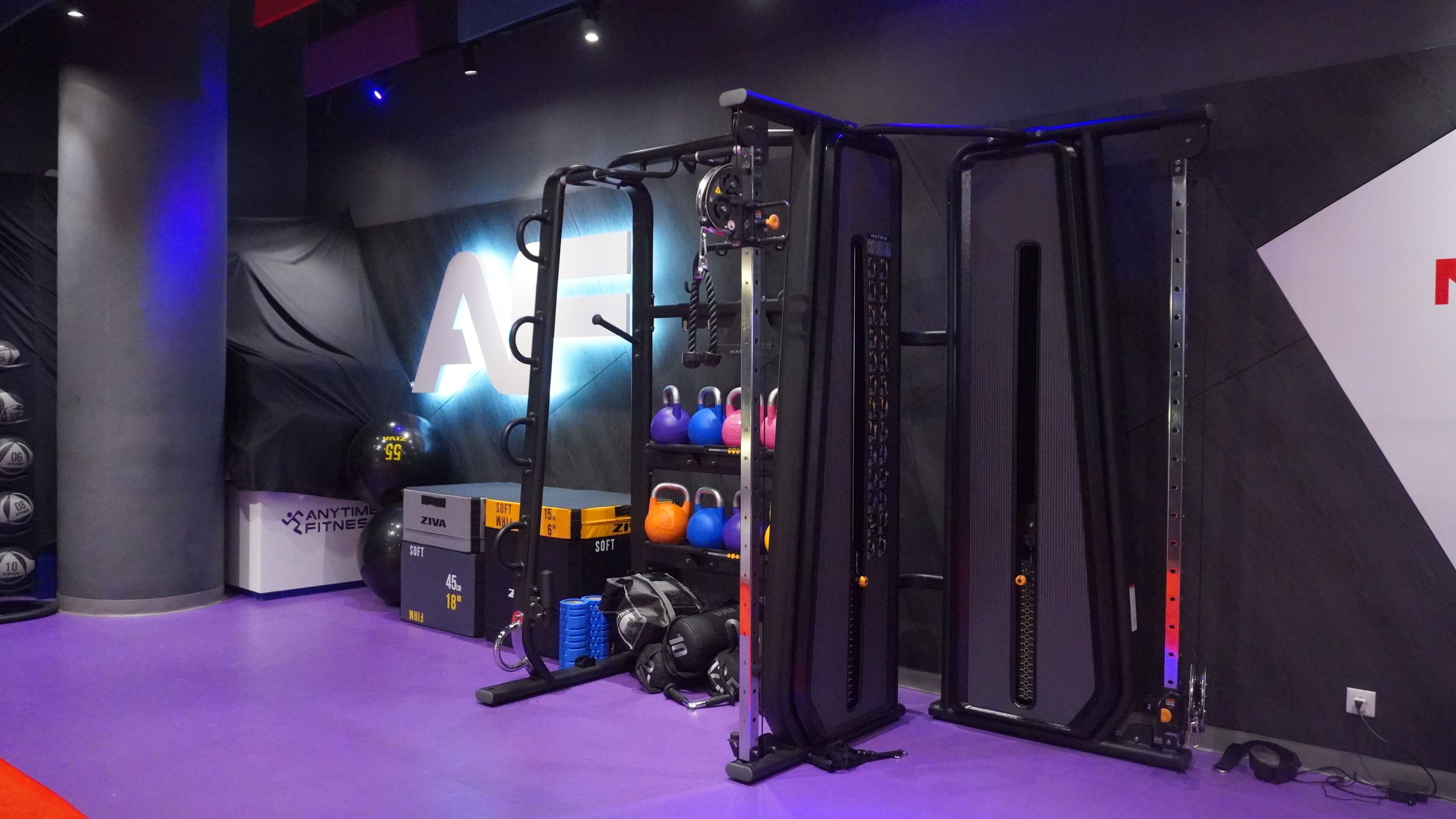 A gym with weightlifting equipment, kettlebells, and a wall-mounted rack.