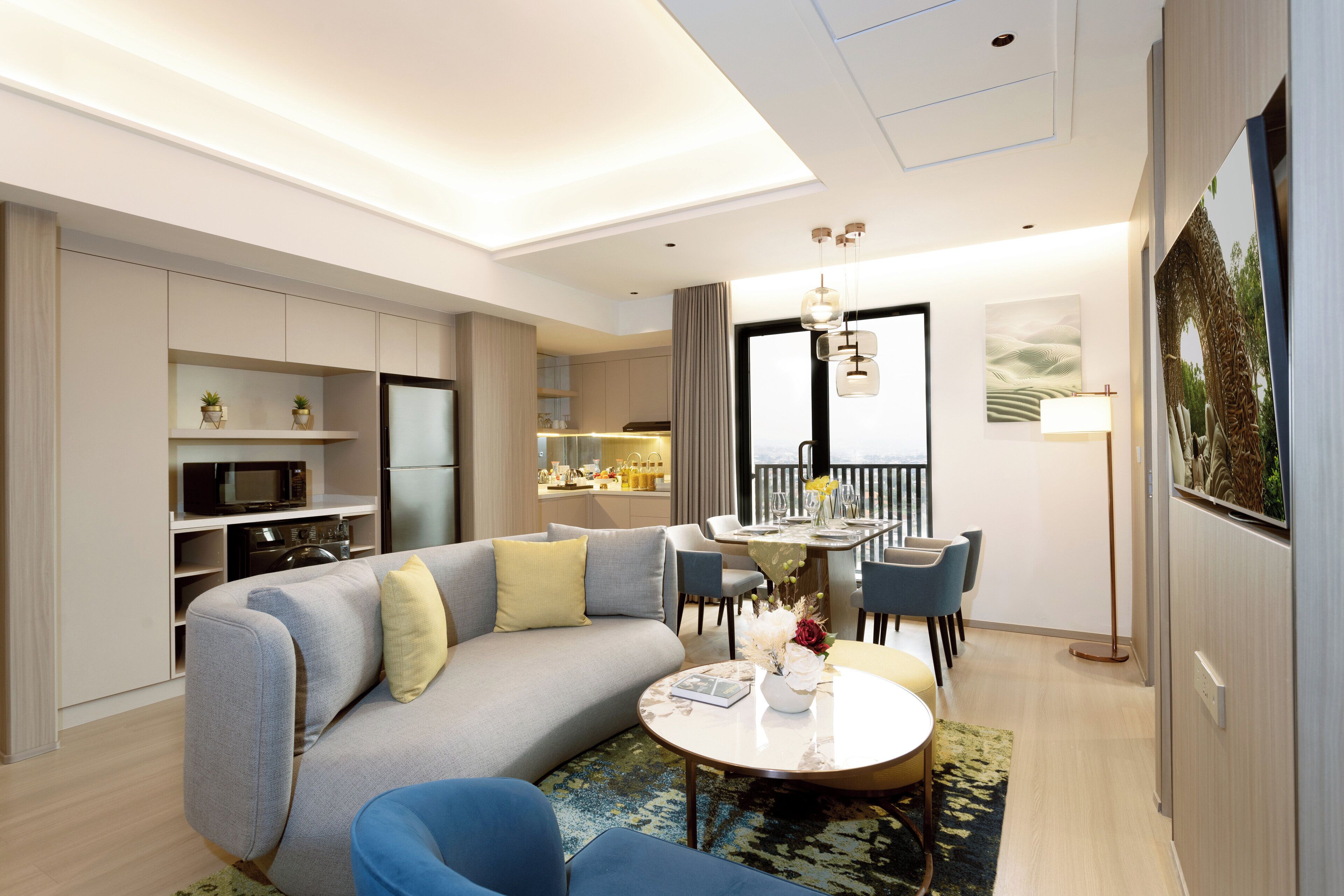 A modern living room with a grey sofa, blue armchairs, a round coffee table, and a dining area with a table and chairs.