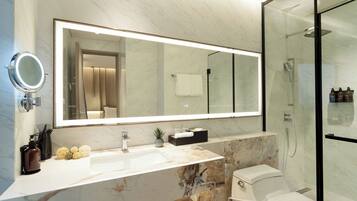 A modern bathroom with a large mirror, a sink, a toilet, and a glass-enclosed shower.