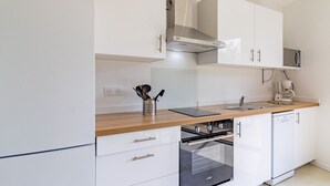 Una cocina moderna con armarios blancos, una campana extractora de acero inoxidable, un horno empotrado y un microondas.