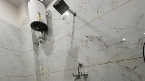 A bathroom with a toilet, a shower, and a water heater. - Hotel Shree Shyam Ras (Jaipur)