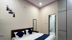 A modern bedroom with a large bed, a mirror, a wardrobe, and a bathroom with a glass door. - Hotel Shree Shyam Ras (Jaipur)