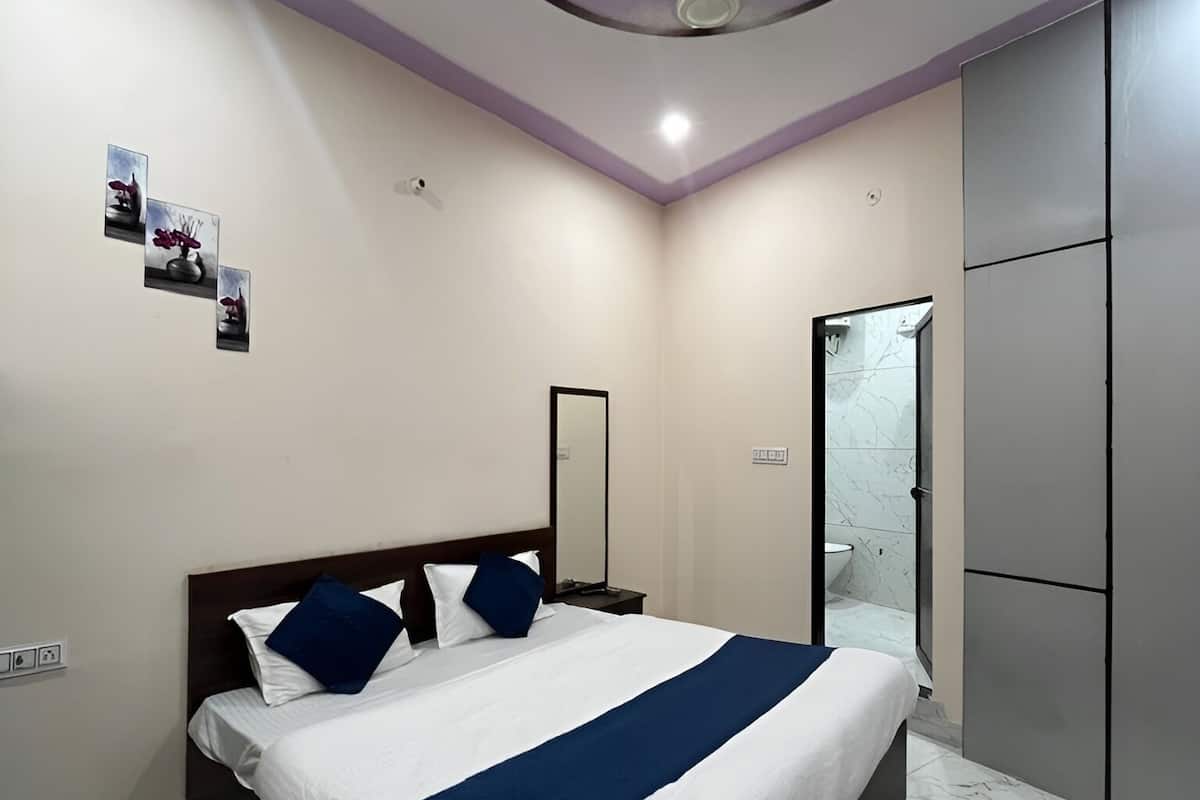 A modern bedroom with a large bed, a mirror, a wardrobe, and a bathroom with a glass door.