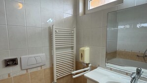 Een badkamer met toilet, wastafel, spiegel, handdoekhouder en een raam.