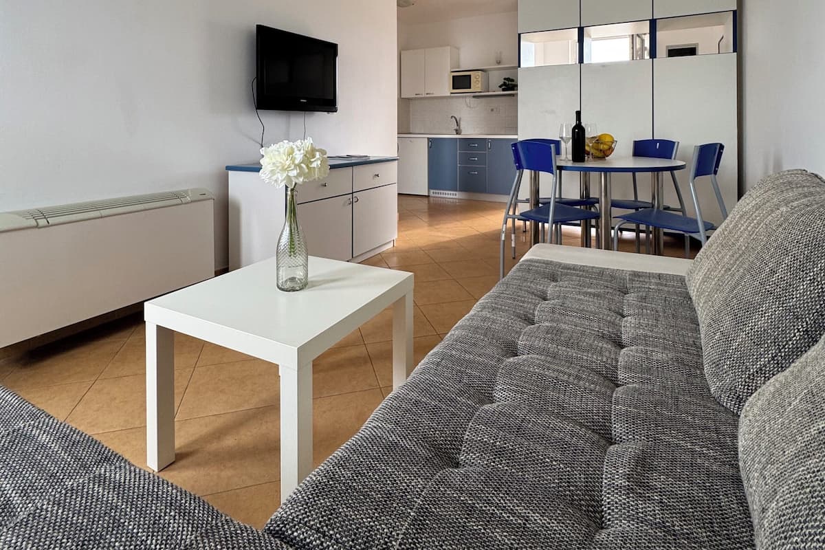 A modern living room with a grey sofa, a white coffee table, and a flat-screen TV mounted on the wall.