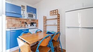 Une cuisine de taille réduite avec des meubles de couleur bleue, une table à manger en bois et des chaises bleues.