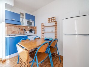 A compact kitchen with blue cabinets, a wooden dining table, and blue chairs. - Apartment for 6 with Wi-Fi and sea view in Roquebrune-Cap-Martin (Roquebrune-Cap-Martin)