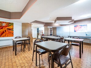 A dining area with tables and chairs, a bookshelf, and a large window.