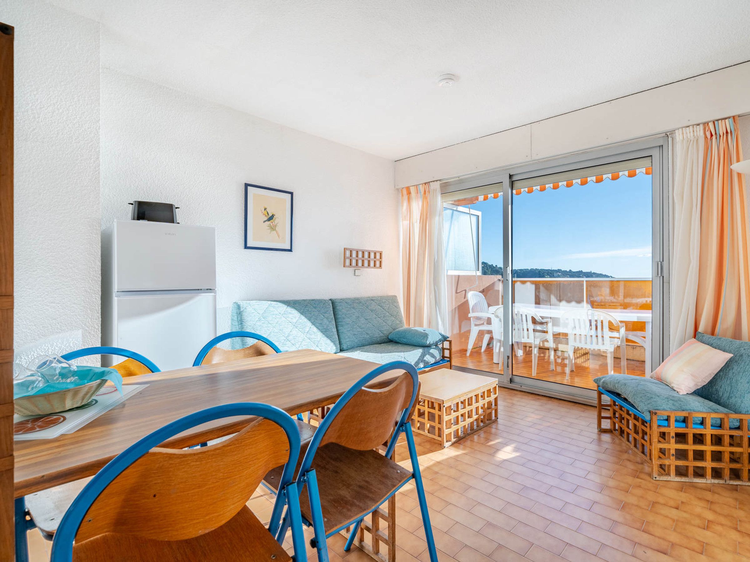 A modern living room with a dining area, a sofa, and a balcony with a view.