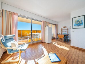 A spacious room with a balcony, a dining area, and a refrigerator.
