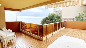 A balcony with a view of the sea, a white table, and two white chairs. - Apartment for 8, sea view, Wi-Fi included (Roquebrune-Cap-Martin)