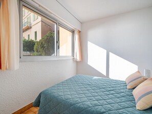 A bedroom with a bed, a window, and a view of buildings outside. - Apartment for 8 people with Wi-Fi in Roquebrune-Cap-Martin (Roquebrune-Cap-Martin)