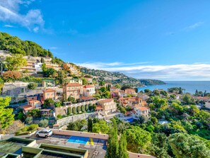Uma cidade costeira com casas em terraços, uma piscina e vista para o mar.