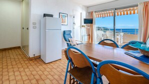 A compact room with a dining table, chairs, a refrigerator, a TV, and a balcony with a view of the sea. - Lovely flat 8 people, terrace with Wi-Fi (Roquebrune-Cap-Martin)