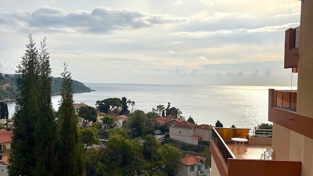 A coastal residential area with houses, trees, and a view of the sea.