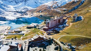 Paisaje montañoso con una gran masa de agua, una estación de esquí y varios edificios, incluyendo un hotel.