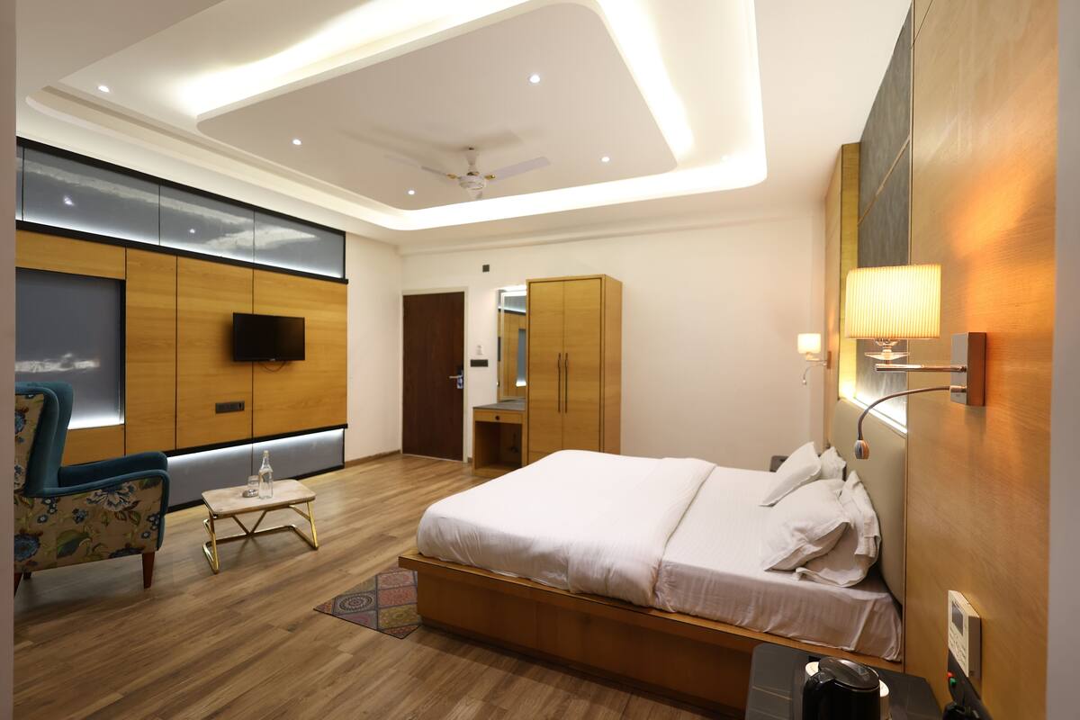 Une chambre d’hôtel moderne dotée d’un grand lit, d’un coin salon avec une chaise et une table, d’une armoire et d’un téléviseur.