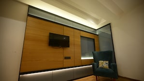 A modern room with a wooden panel wall, a flat-screen TV, and a teal armchair. - Vasuh Mhangglam (Bilha)