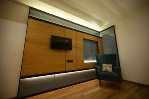 Una habitación moderna con un panel de madera en la pared, un televisor de pantalla plana y un sillón turquesa.