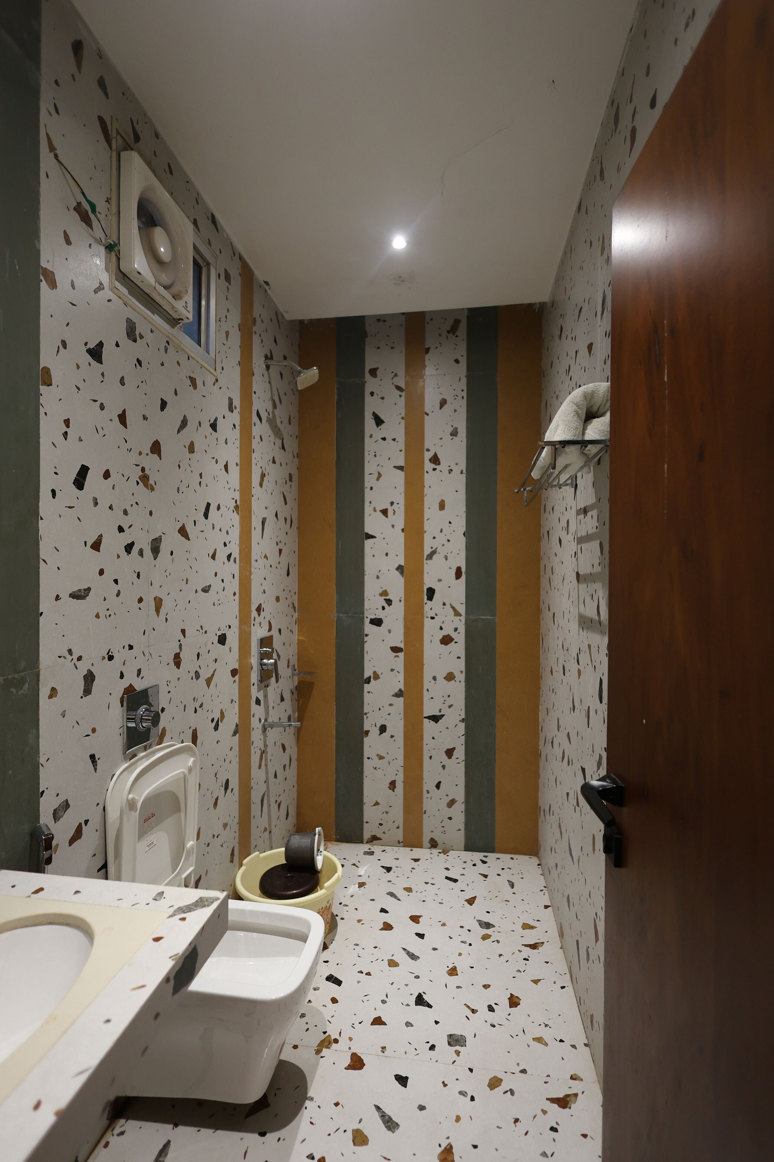 A bathroom with a white sink, two urinals, a toilet, and a shower area.