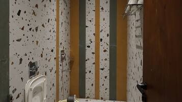 A bathroom with a white sink, two urinals, a toilet, and a shower area.