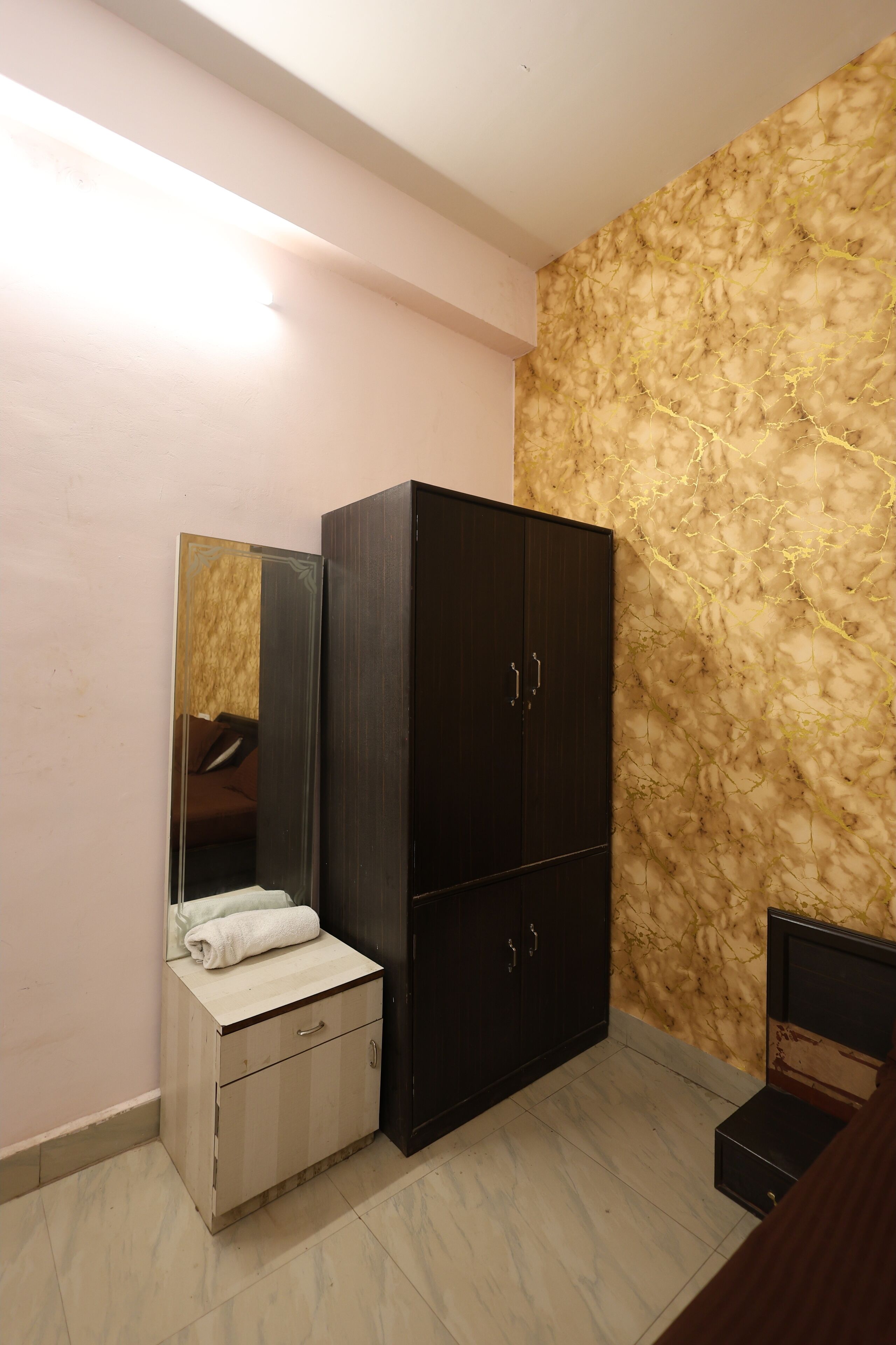 Un dormitorio con una cama, un armario, un espejo y una pared con un diseño texturizado.