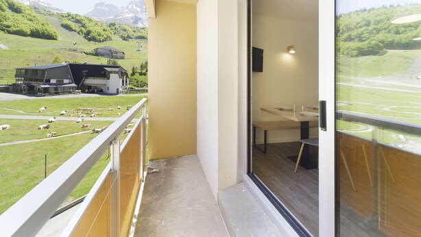 A balcony with a view of a green landscape and a building with a mountain backdrop. - Renovated studio in Gourette, 4 people, pets allowed, wifi (Gourette)
