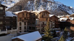 Un edificio in stile chalet in legno, con balconi e pareti in pietra, immerso tra montagne innevate.
