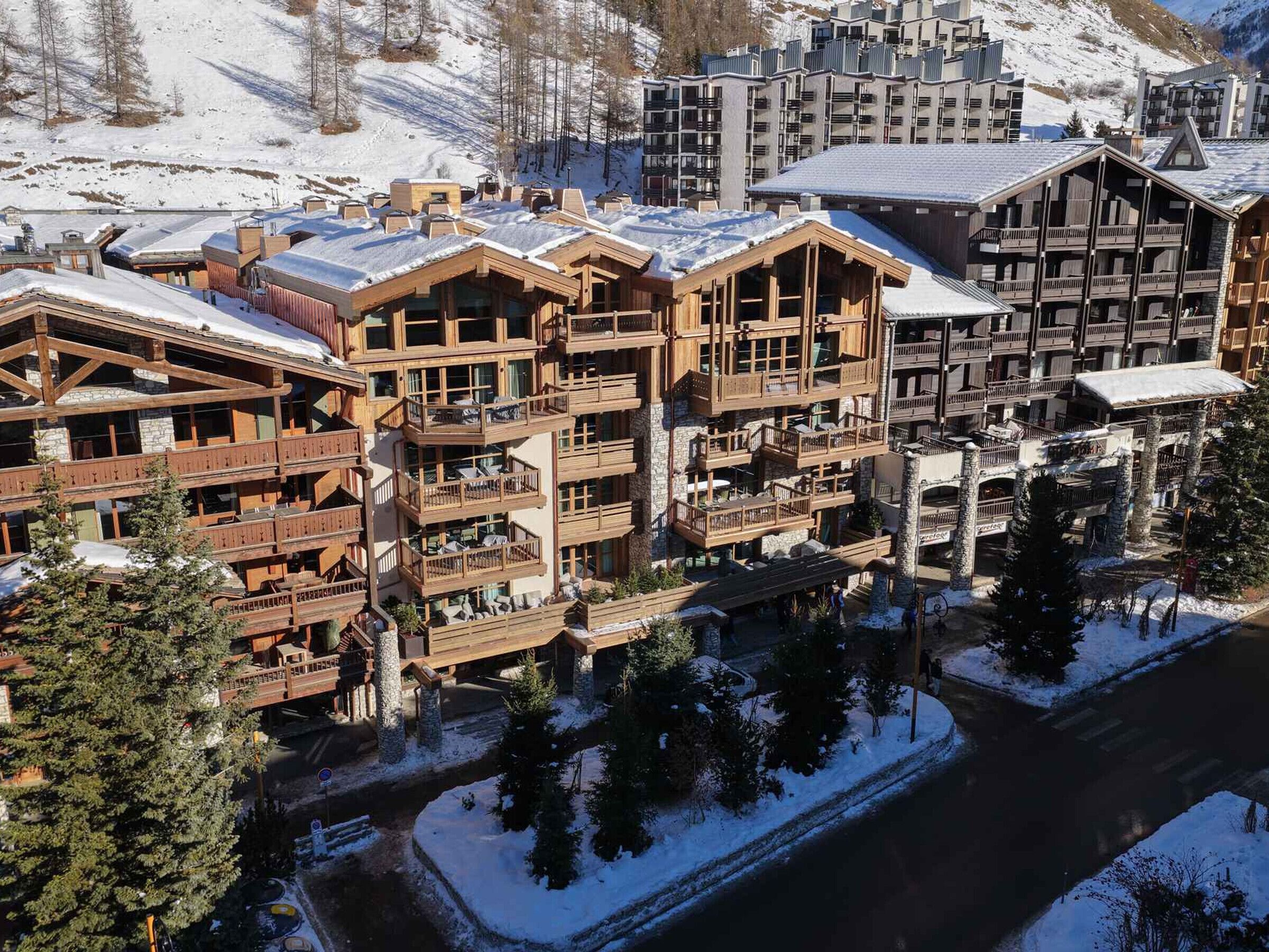 A multi-story lodge with wooden balconies and a ski slope in the background.