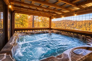 Un bain à remous avec une terrasse en bois et une vue sur le feuillage automnal.
