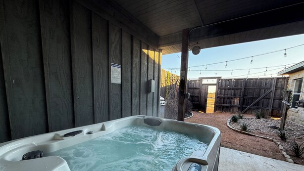 Un jacuzzi bajo una estructura de madera con un cartel que indica instrucciones de seguridad.