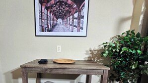 Una mesa de madera rústica con dos bancos acolchados, un cuadro enmarcado encima y una planta en maceta al lado.