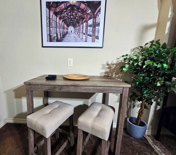 Una mesa de madera rústica con dos bancos acolchados, un cuadro enmarcado encima y una planta en maceta al lado.