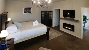 Un dormitorio con cama, televisión, chimenea y candelabro.