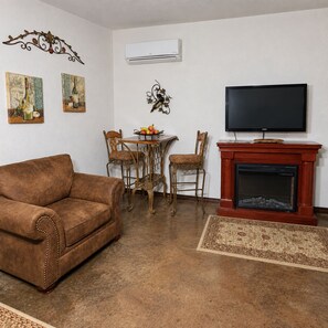 A living room with a brown sofa, a fireplace, a television, and a dining table with chairs.