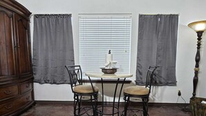 A room with a dining table, two chairs, a cabinet, and a lamp. - Wine Trail Cottage · Hot Tub, Pool & Wineries (Fredericksburg)